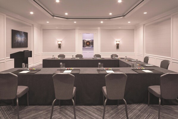 Une salle de conférence avec une longue table, des chaises et un pupitre.