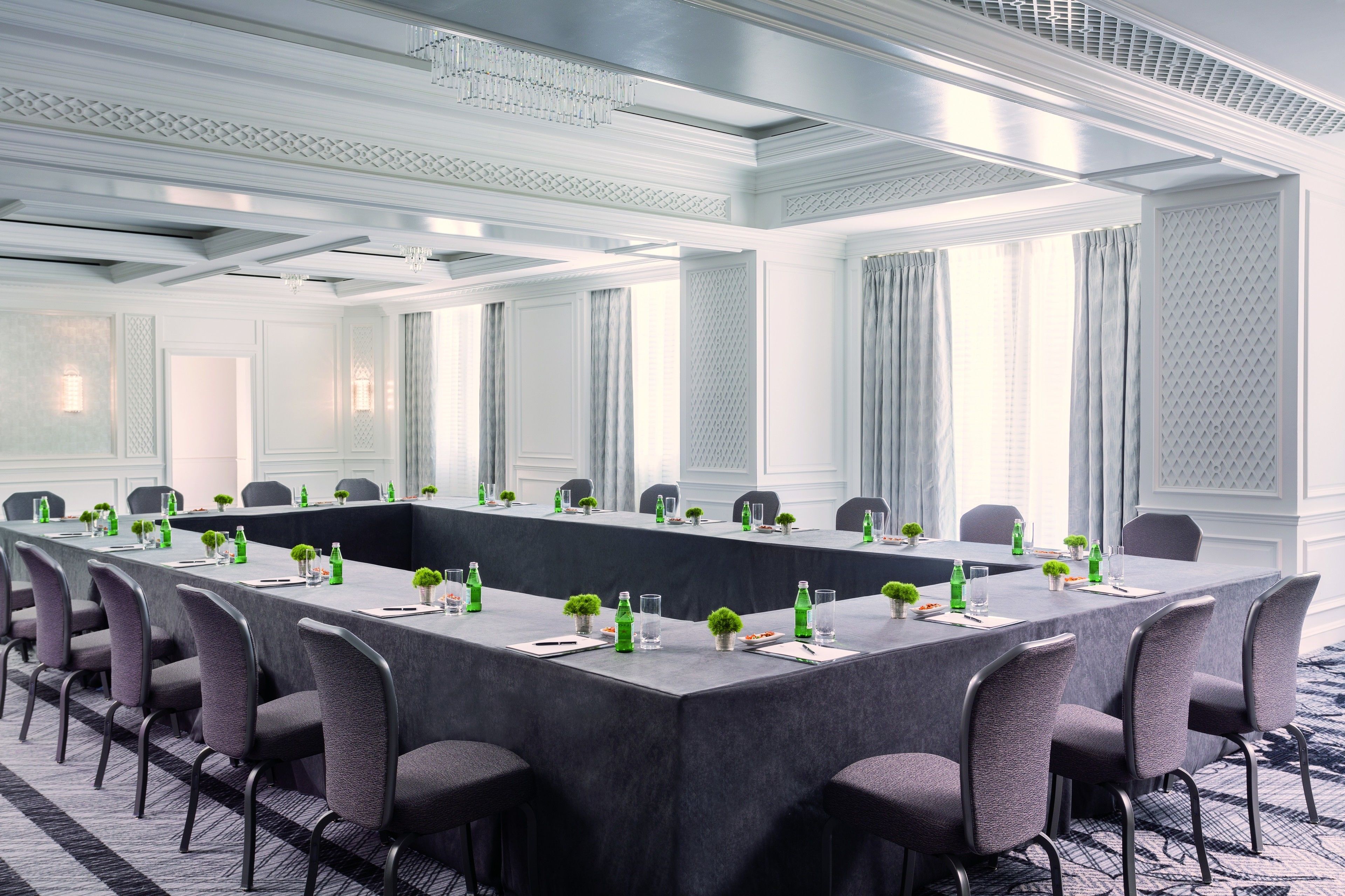A conference room with a long table, chairs, and a carpeted floor.