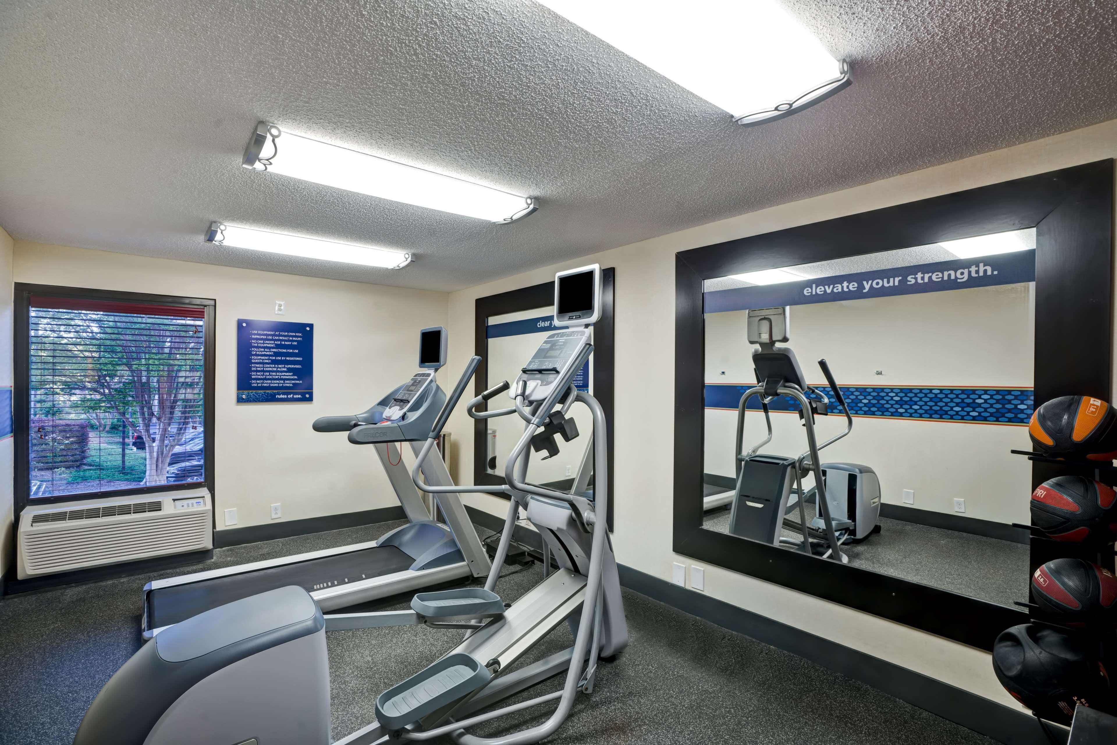 Un gimnasio con cintas de correr, elípticas y un espejo con mensajes motivacionales.