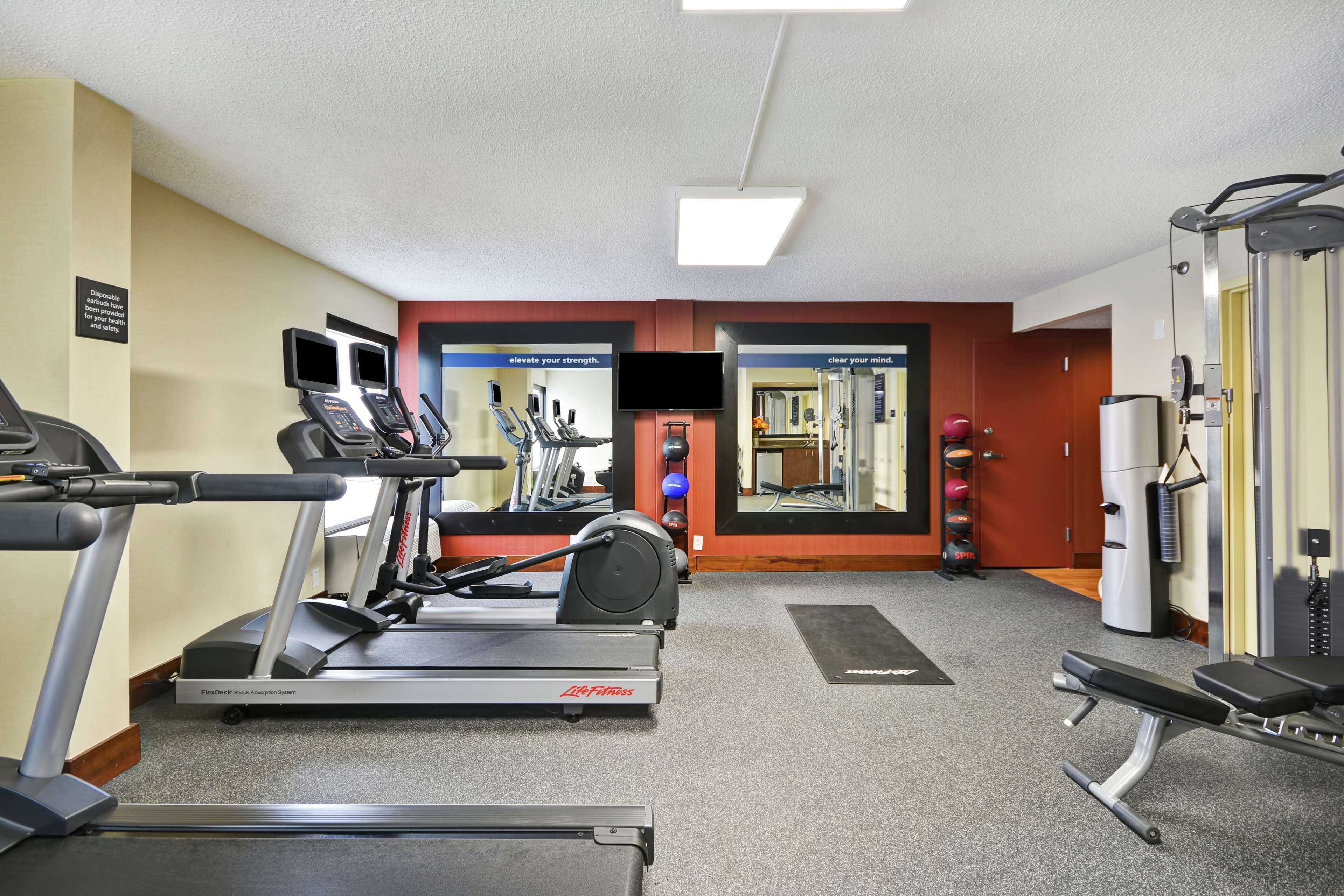 Une salle de sport équipée de tapis de course, d’un rameur et d’un banc de musculation.