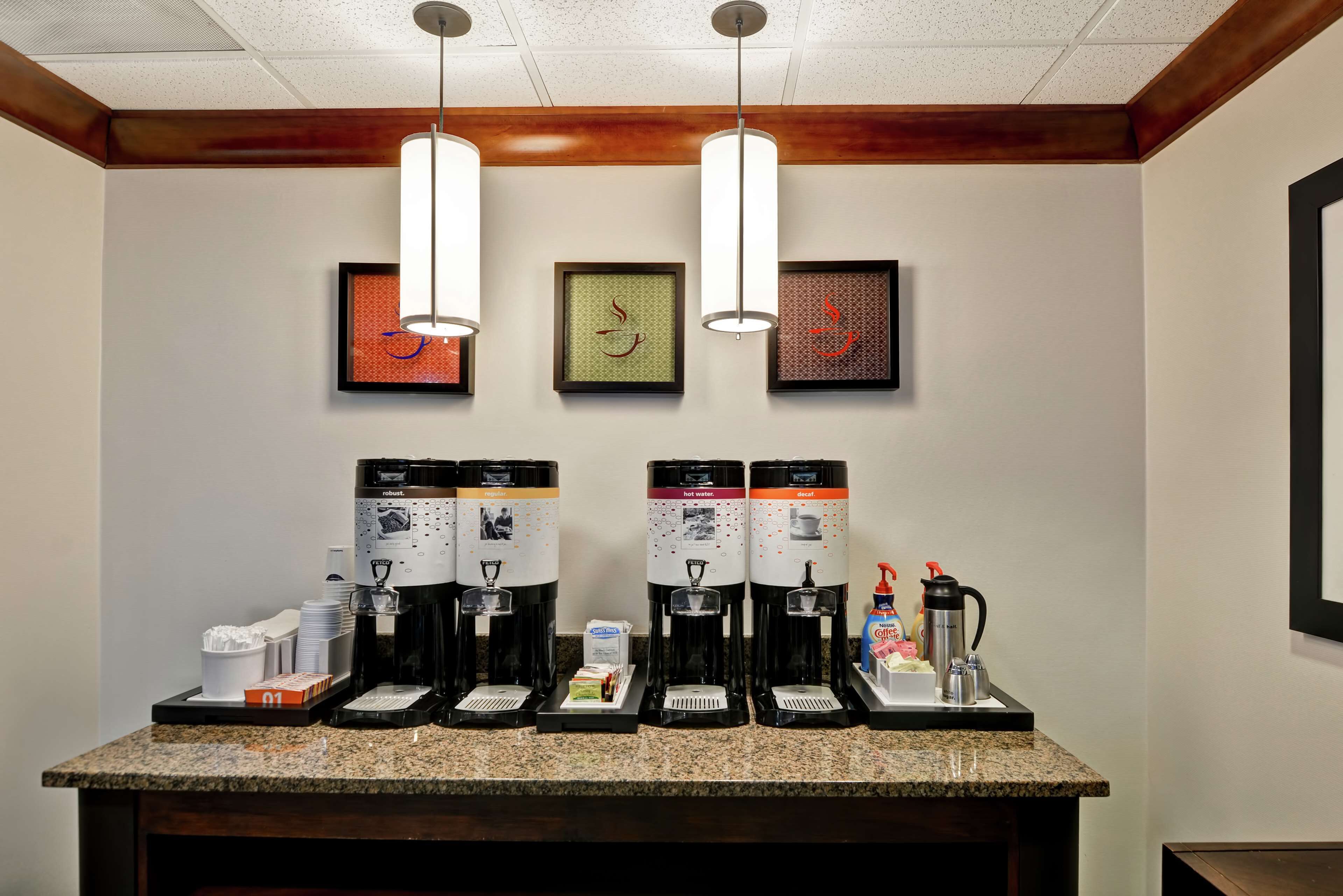 Una estación de café con cuatro dispensadores, una cafetera y un espumador de leche.