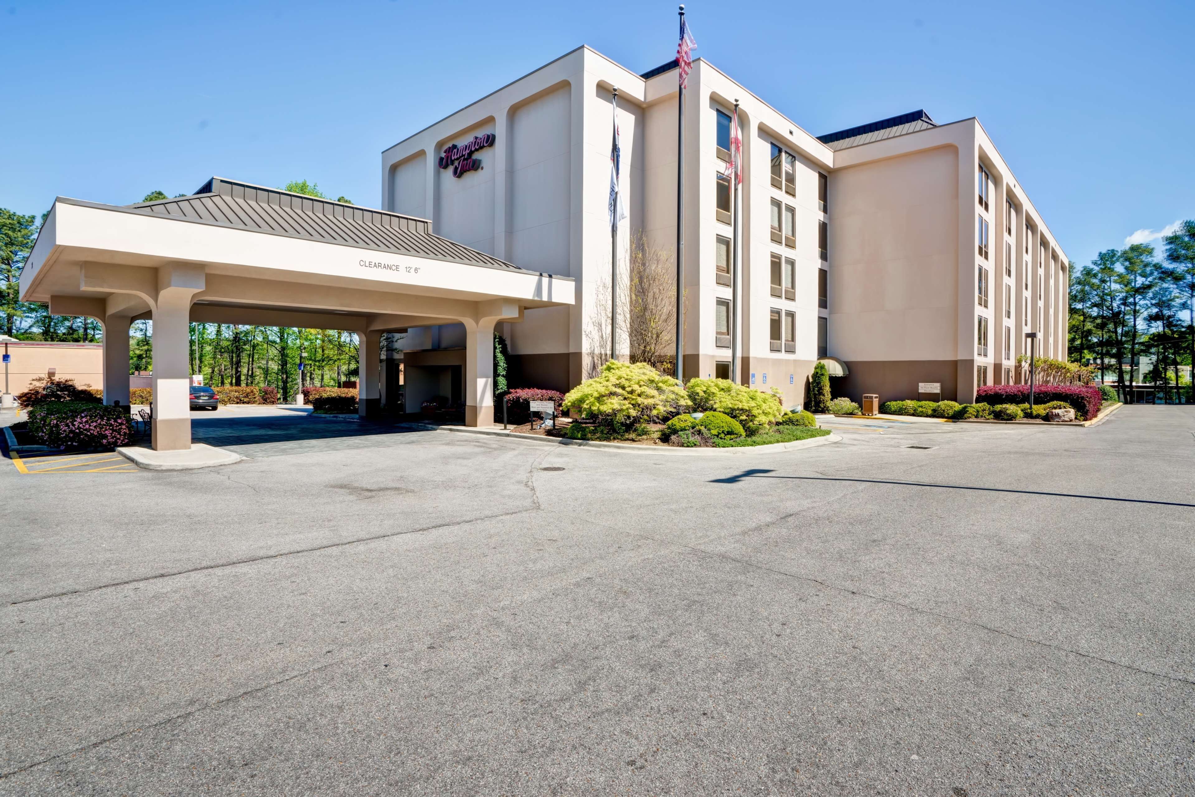 A Hampton Inn with a covered entrance, flag, and landscaped garden.