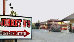 Cartell de 'Johnny B's HomeRun Cooking' amb un edifici al fons.