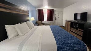 Habitació d'hotel amb llit, escriptori, televisió i armari.