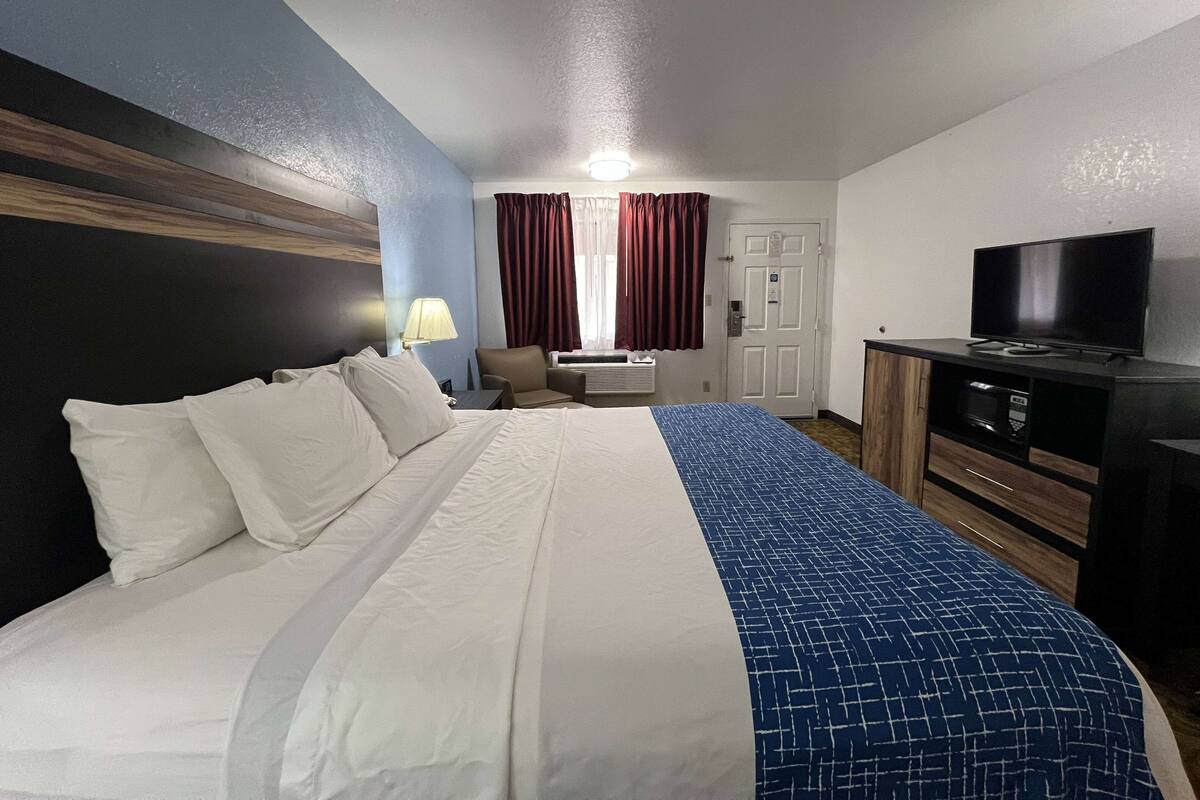 A hotel room with a bed, a desk, a television, and a wardrobe.