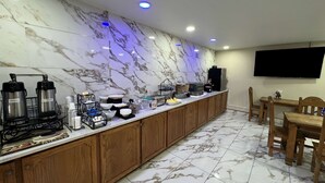 A hotel kitchen with marble countertops, coffee makers, a TV, and wooden cabinets. - Travelodge by Wyndham Truth or Consequences (Truth or Consequences)