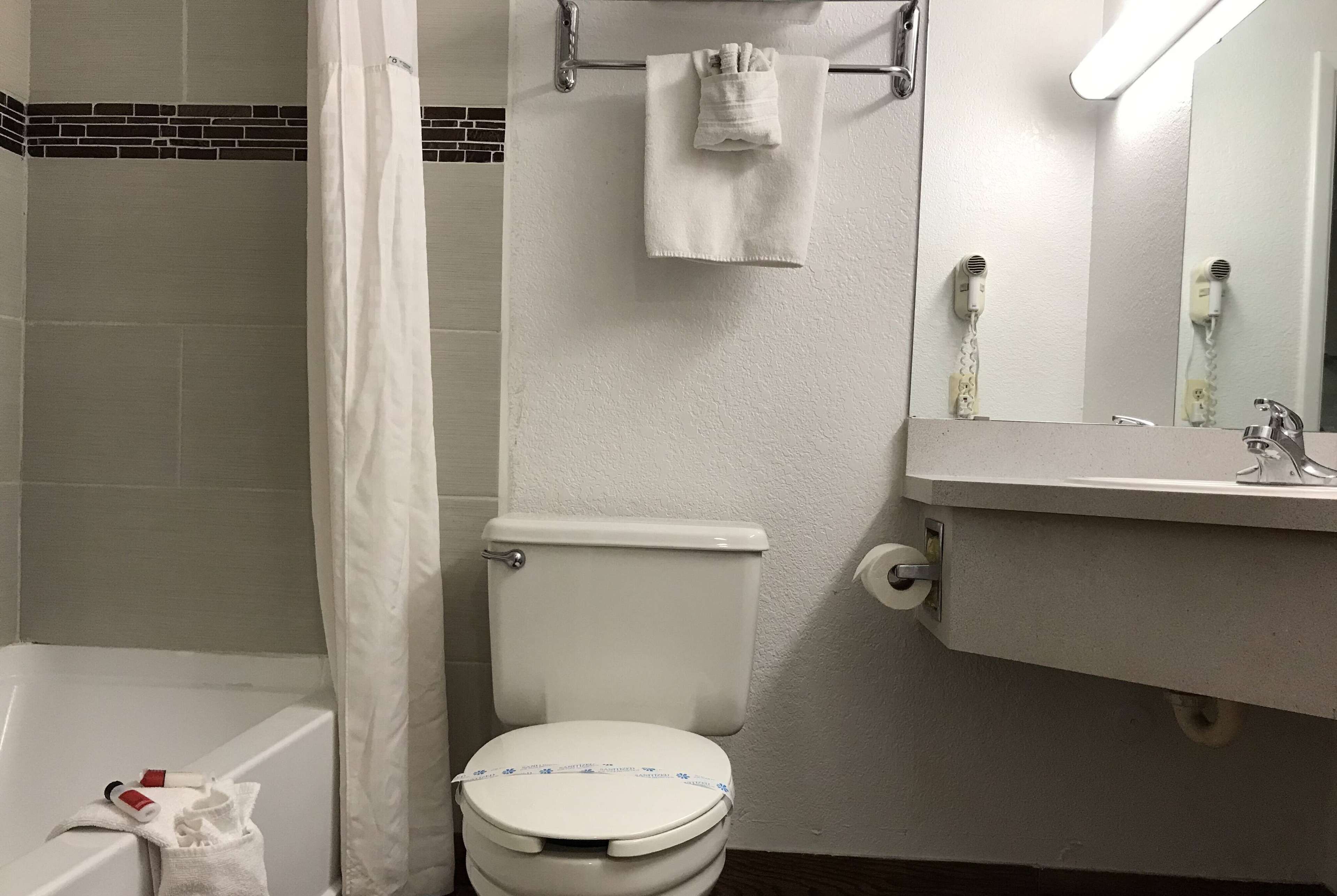 A bathroom with a toilet, a bathtub, a towel rack, and a mirror.