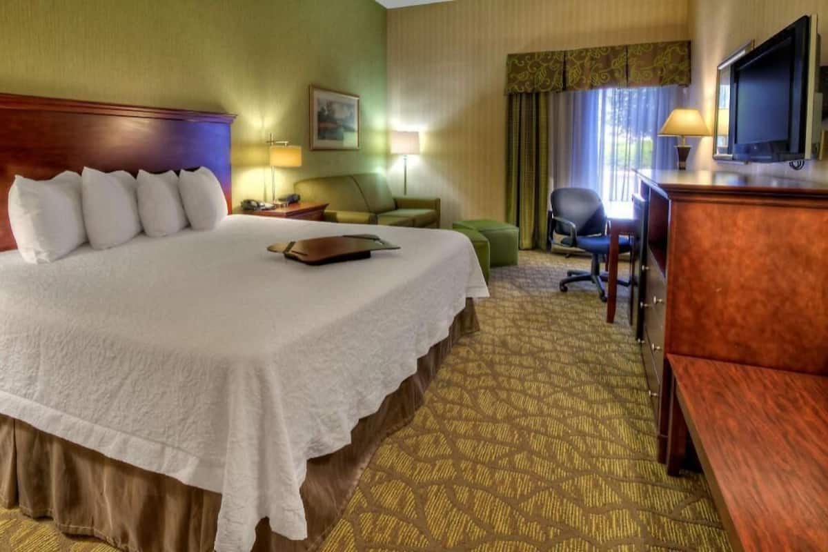 Een hotelkamer met een groot bed, een bureau, een stoel, een televisie en een lamp.