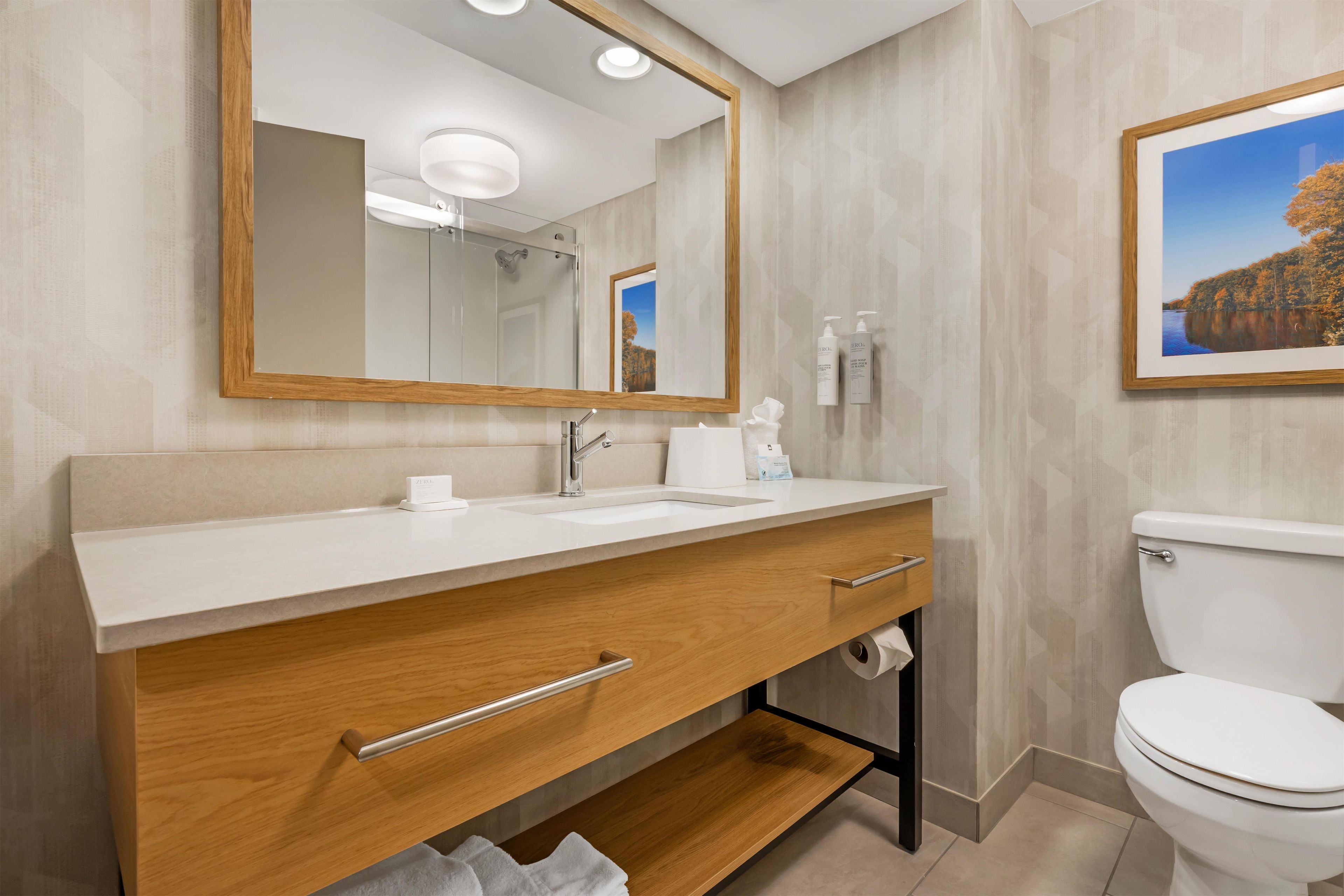 Un baño moderno con tocador de madera, lavamanos blanco y un inodoro.