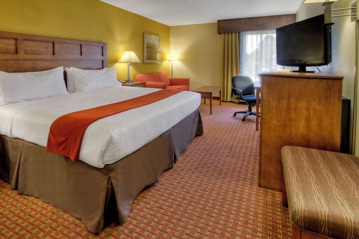 Een hotelkamer met een groot bed, een bureau, een stoel en een televisie.
