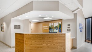 A reception desk with a wooden finish and a welcome sign.