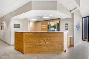 A reception desk with a wooden finish and a welcome sign.