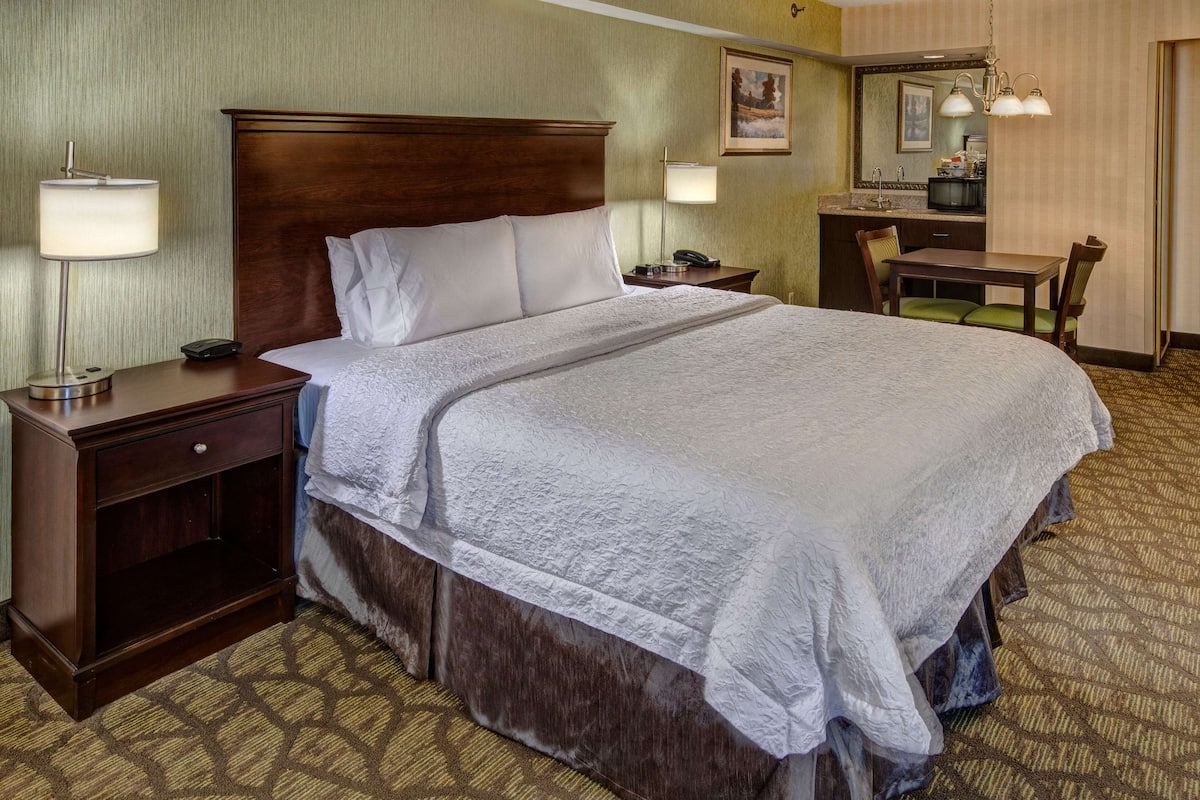 Een hotelkamer met een groot bed, nachtkastje, bureau en stoel.