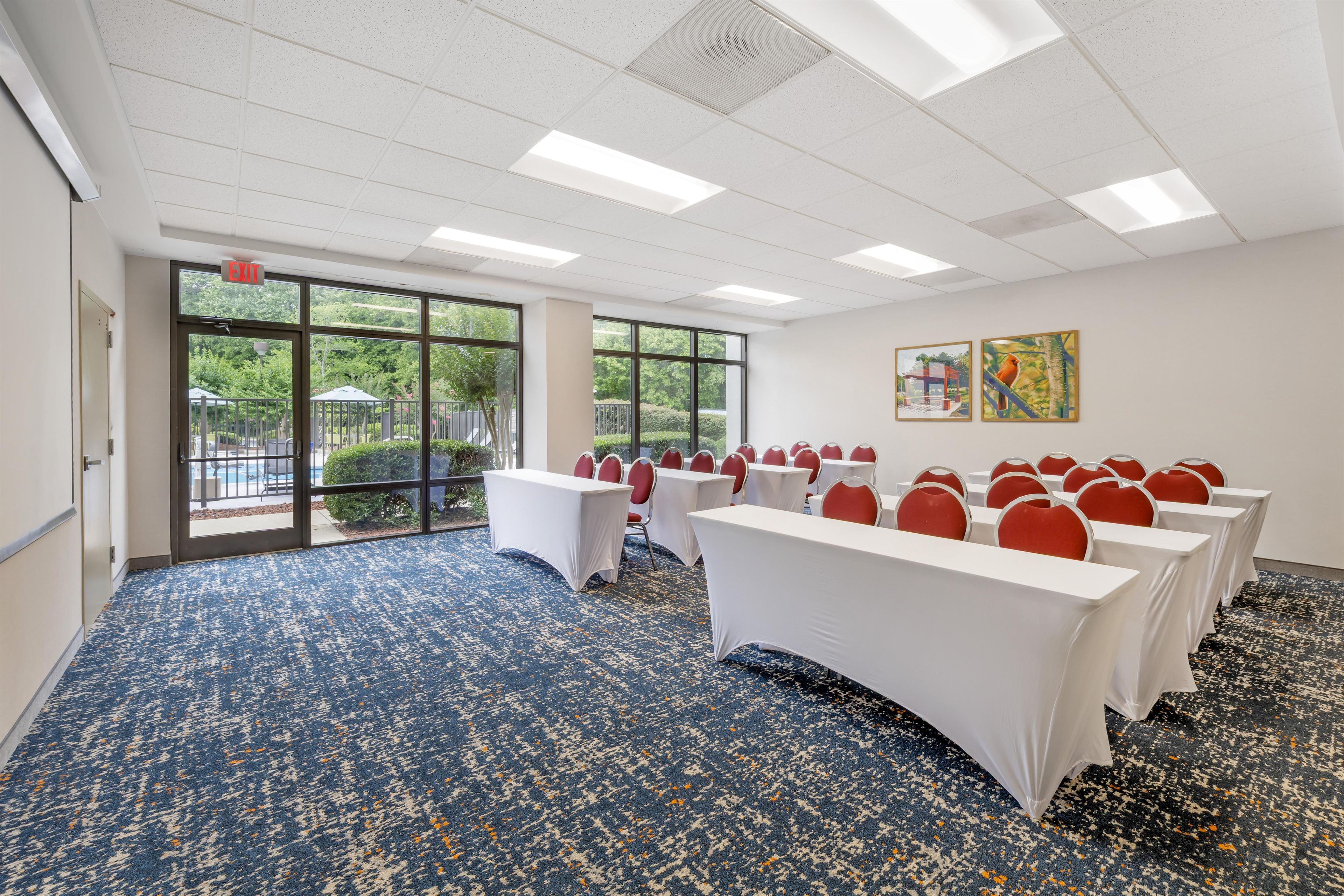 Un salón de conferencias con mesas, sillas, ventanas amplias y obras de arte en la pared.