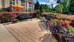 A paved outdoor area with two benches and a large planter with flowers.