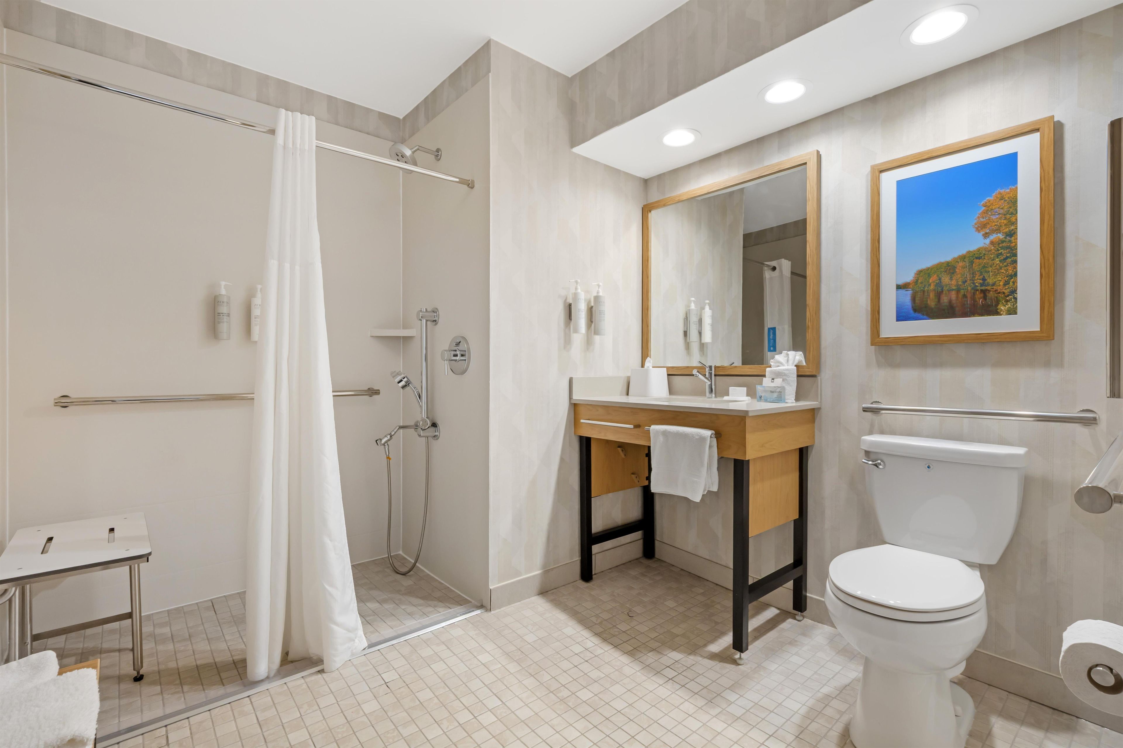 A modern bathroom with a shower, toilet, sink, and a large mirror.