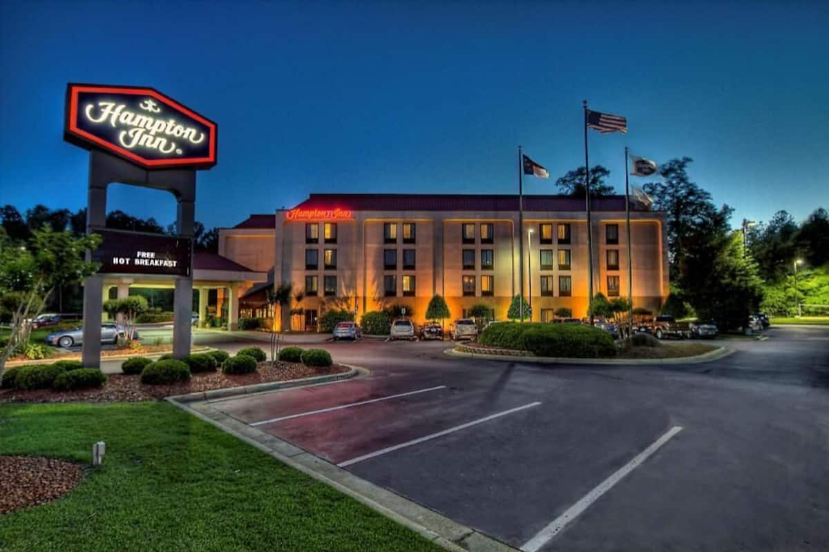 Een Hampton Inn hotel met een bord, een parkeerplaats en een vlag.