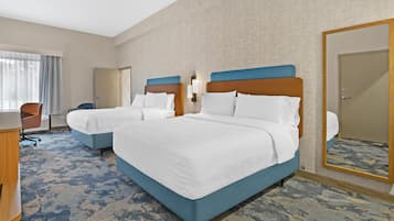 A hotel room with two beds, a desk, a chair, and a large mirror.