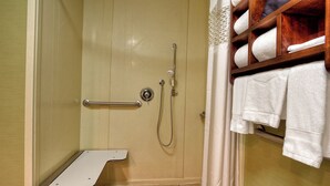 A shower area with a grab bar, a towel rack with towels, and a shower control panel.