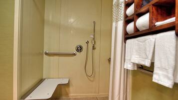 A shower area with a grab bar, a towel rack with towels, and a shower control panel.
