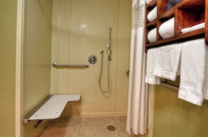 A shower area with a grab bar, a towel rack with towels, and a shower control panel.