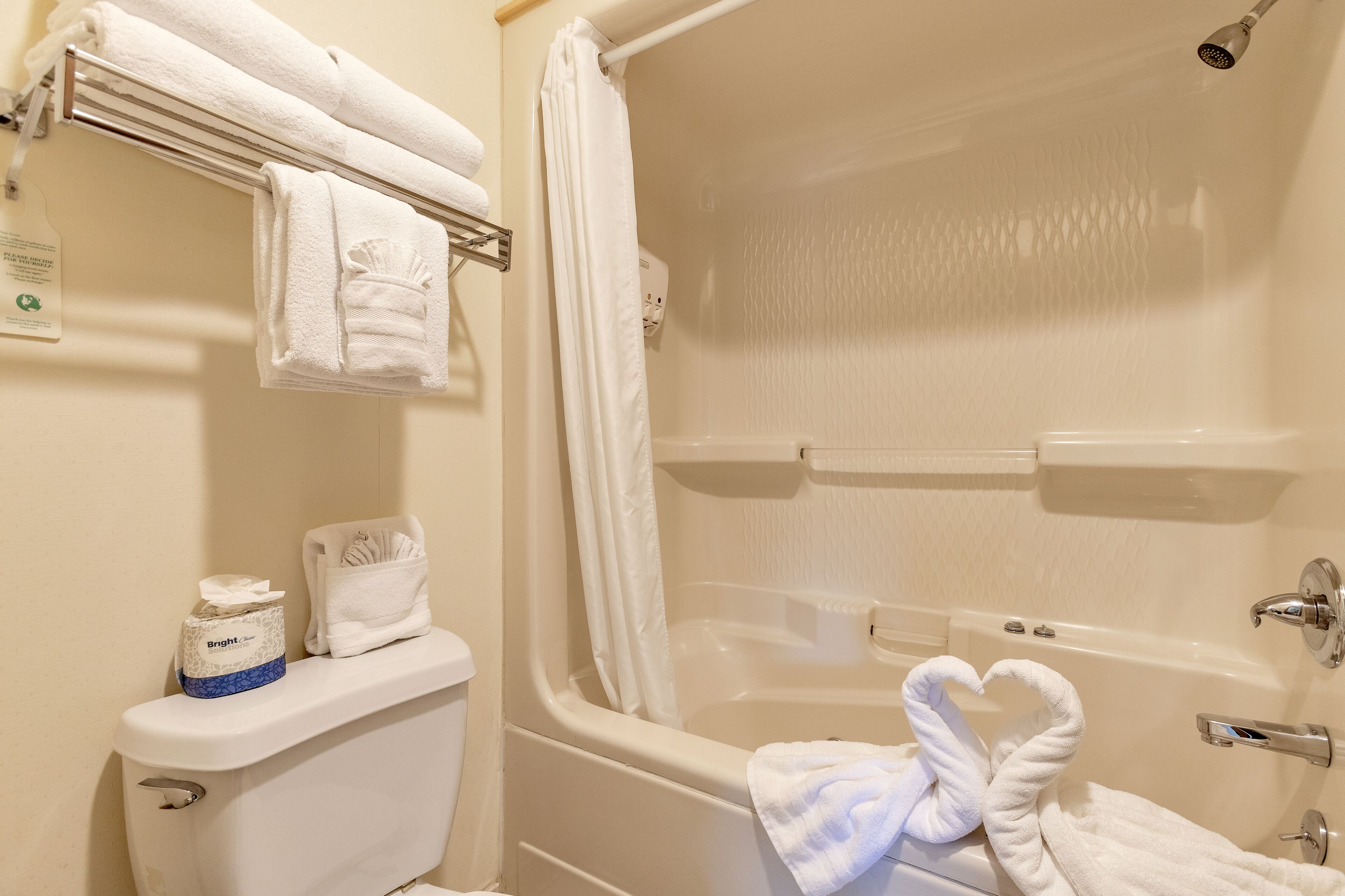 A bathroom with a bathtub, a toilet, and a towel rack with folded towels.