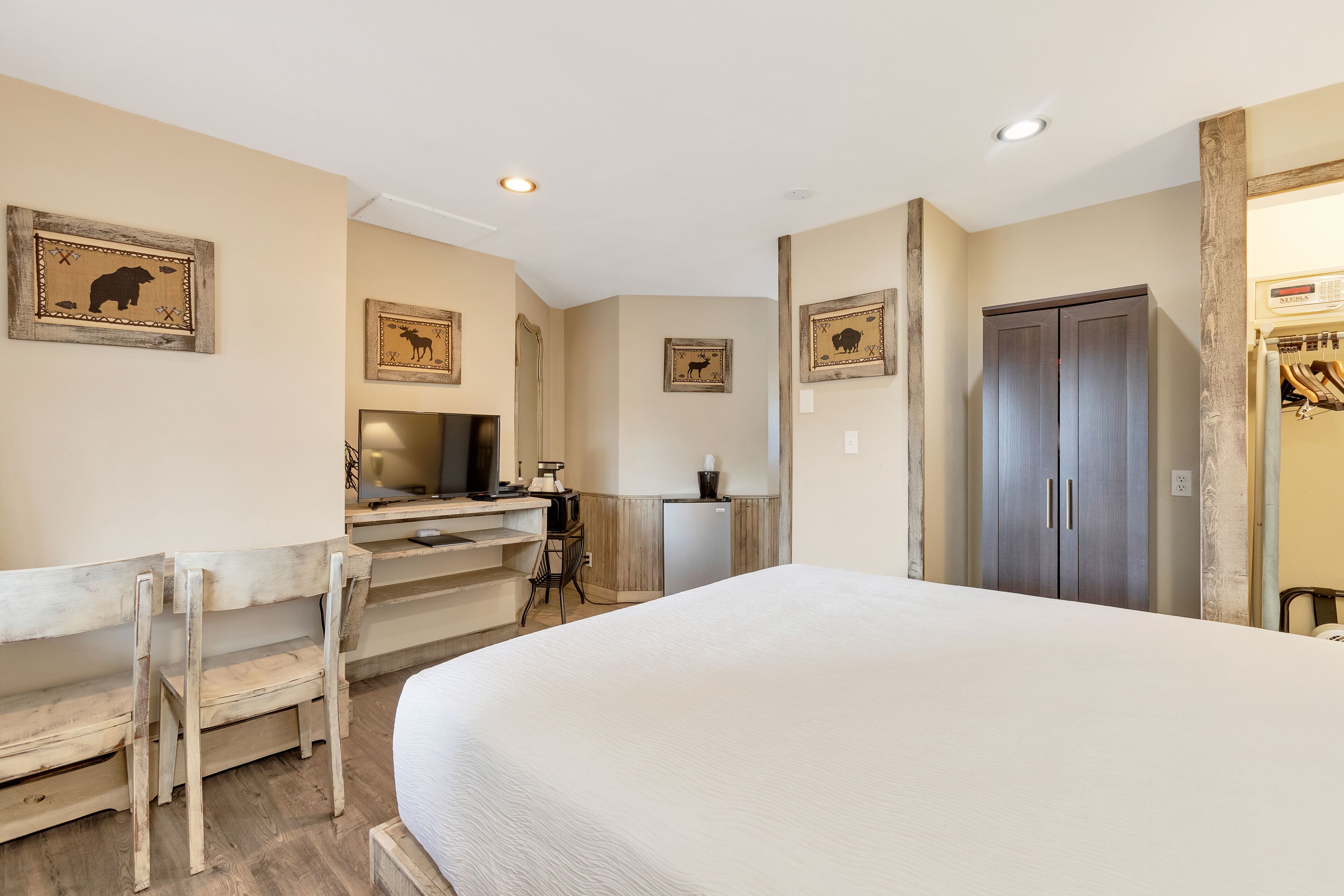 A bedroom with a bed, a desk with a chair, a television, and a wardrobe.