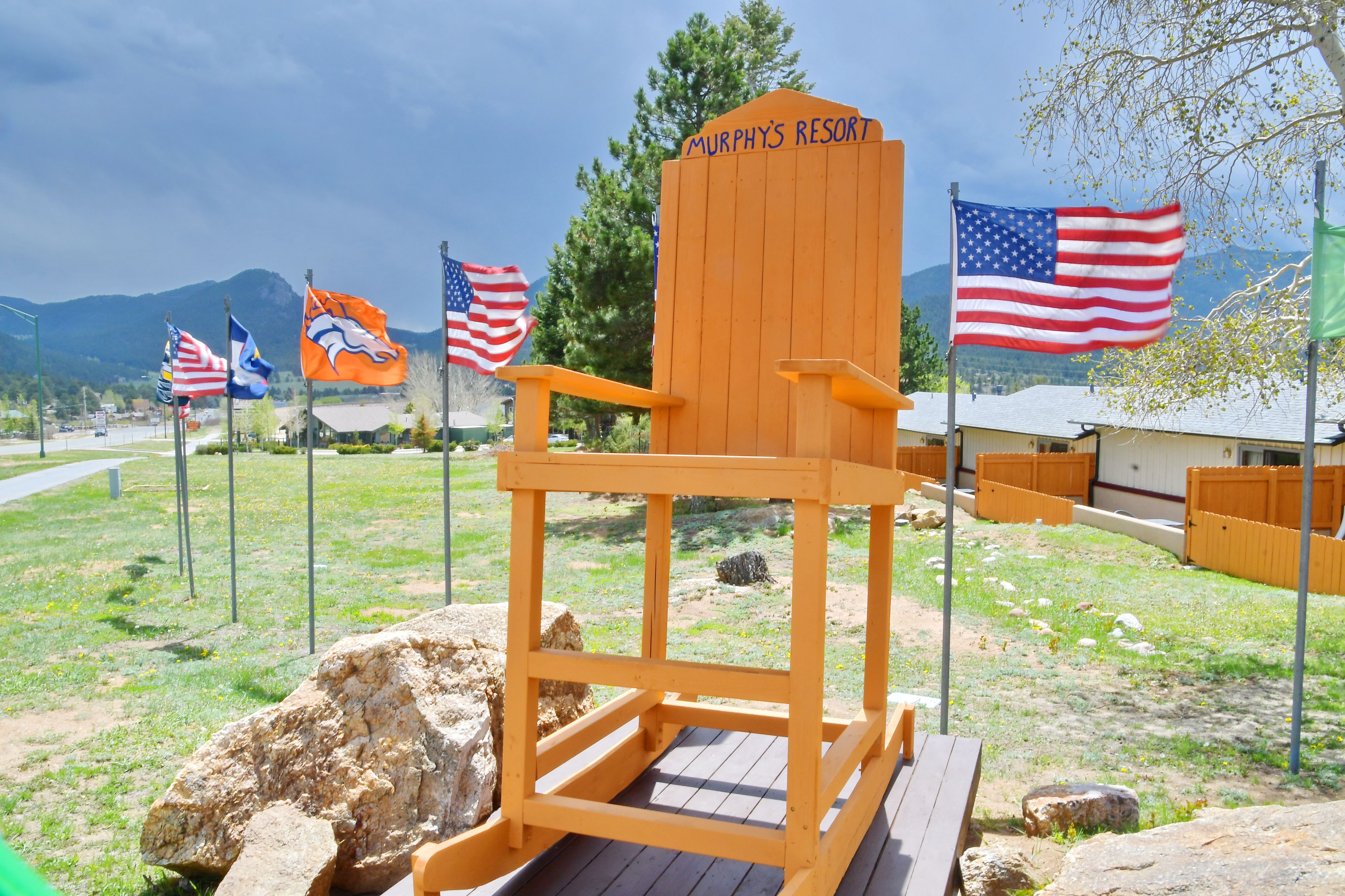 Une chaise en bois portant l’inscription « Murphy’s Resort », entourée de drapeaux, avec une chaîne de montagnes en arrière-plan.
