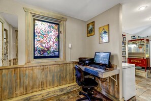 A home office with a computer desk, a chair, a stained glass window, and a popcorn machine.