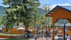 Un espace extérieur aménagé en terrasse, avec des tables et des chaises, une pergola en bois et une fontaine décorative.
