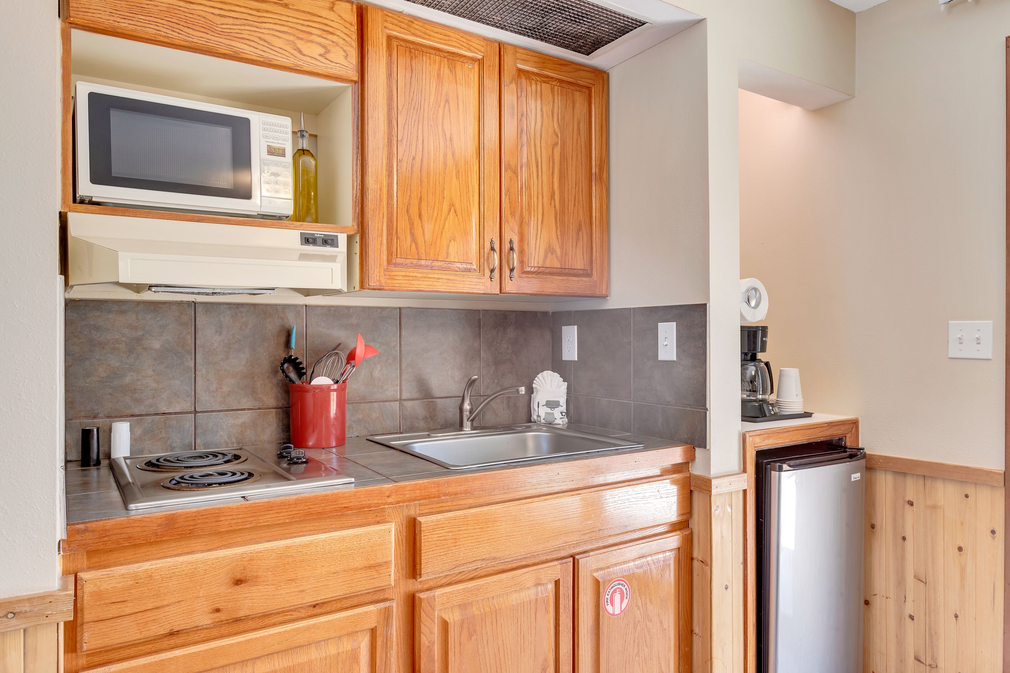 A kitchen with wooden cabinets, a microwave, a sink, a stove, and a refrigerator.