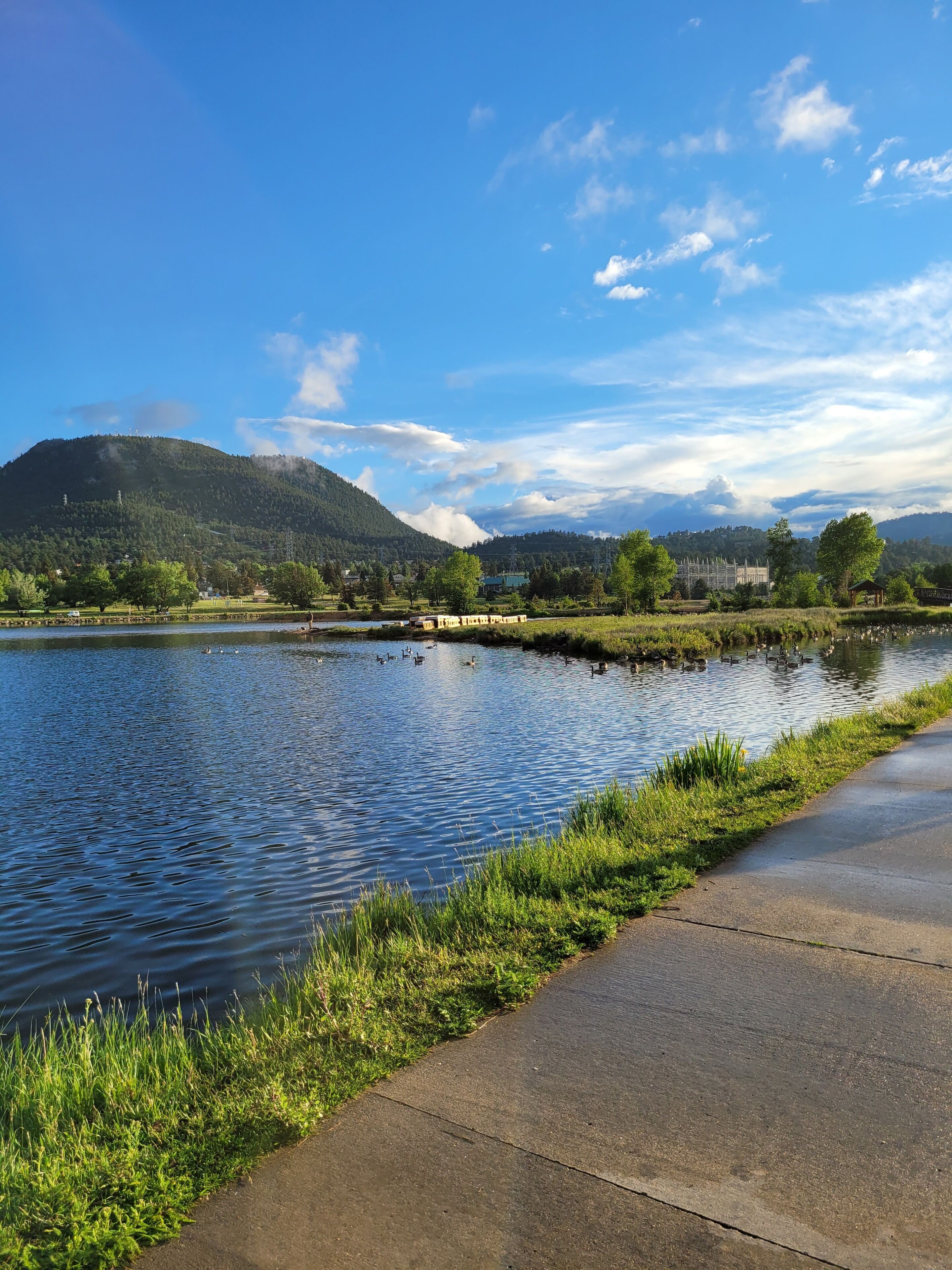 A riverside walkway with a view of a mountain and a clear sky.
