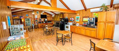 A spacious room with wooden floors, a ceiling fan, and a kitchen area with wooden cabinets and appliances.