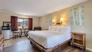 A hotel room with a large bed, a desk with a computer, a chair, and a view of the outside.