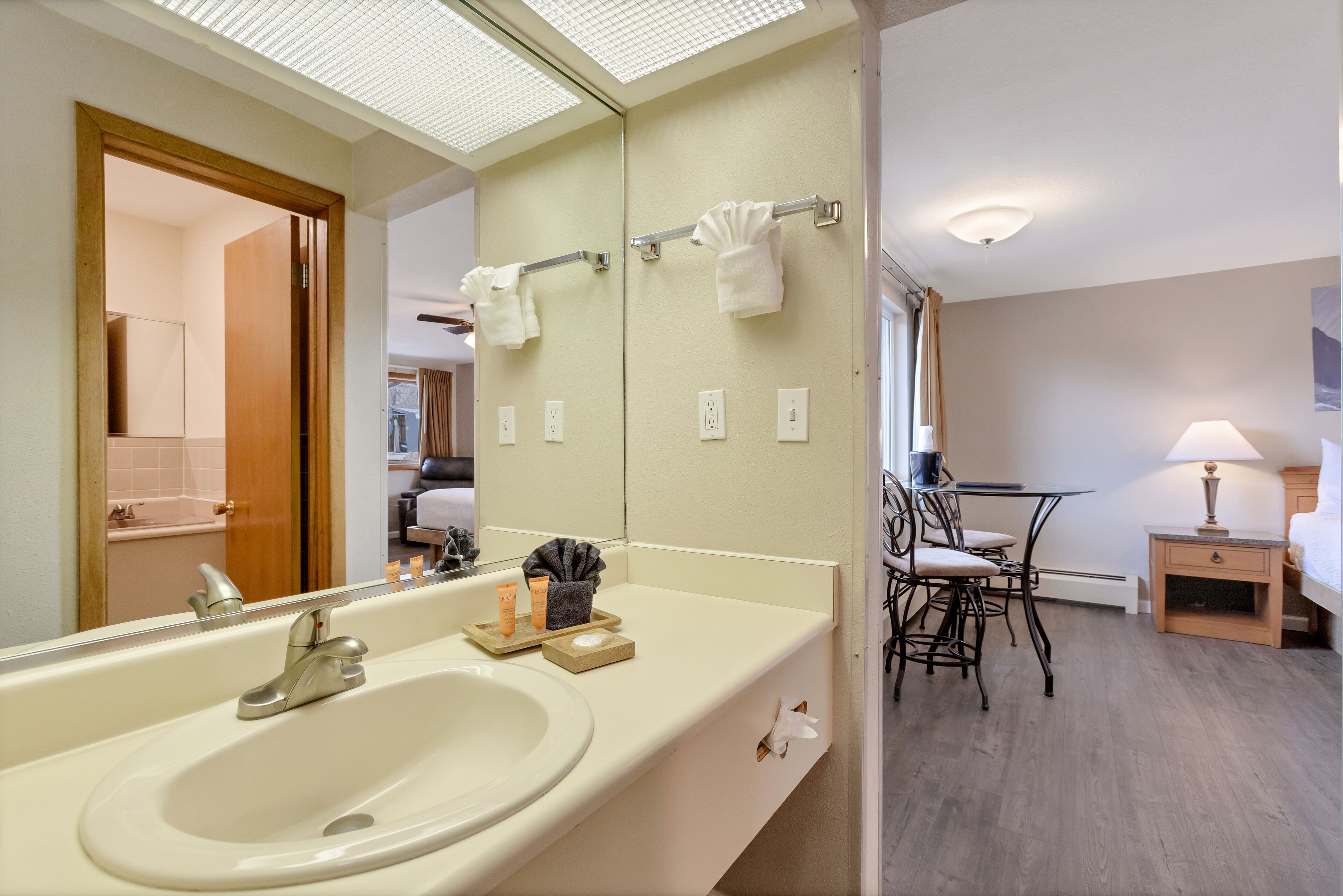 A hotel bathroom with a large mirror, sink, and towel rack.