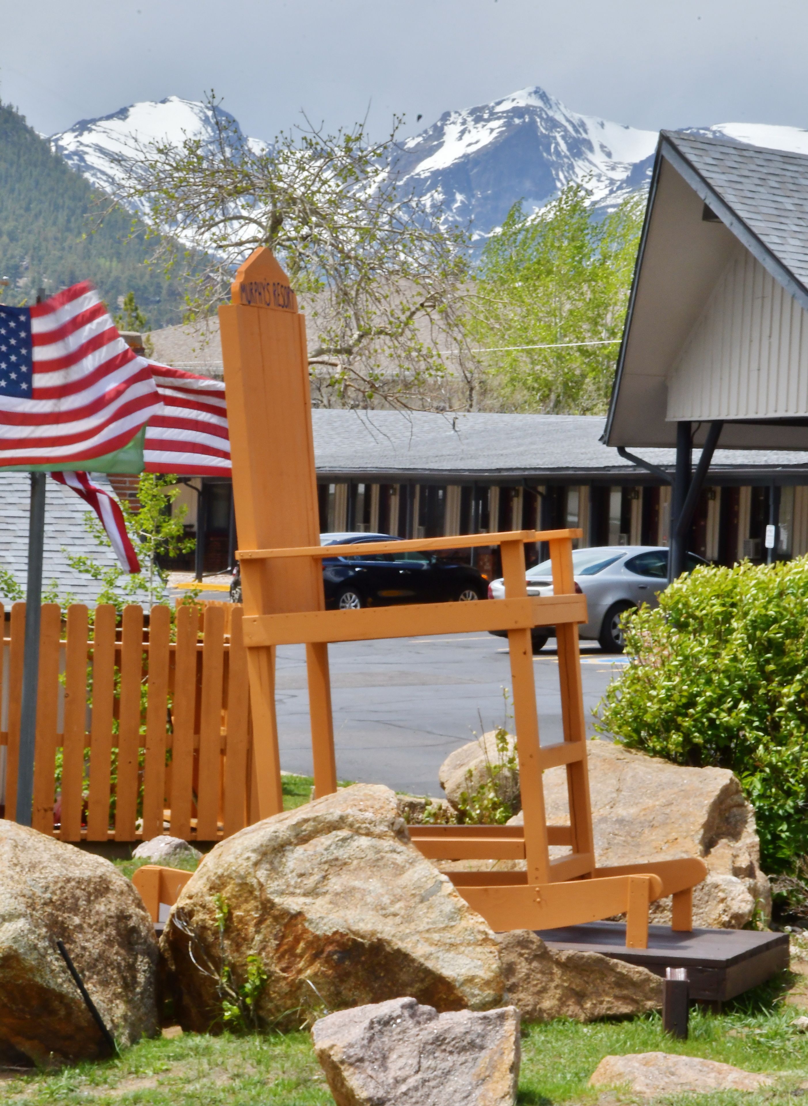 A wooden chair with a sign, a flag, and a mountain backdrop.