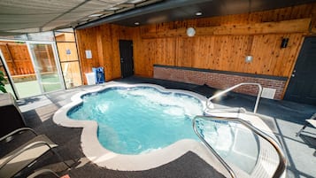 Un jacuzzi con borde de azulejos, una escalera metálica y una pared de madera con un reloj.