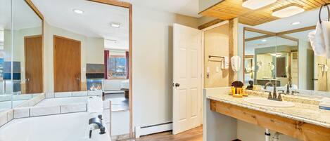 A bathroom with a large mirror, wooden vanity, and a bathtub.