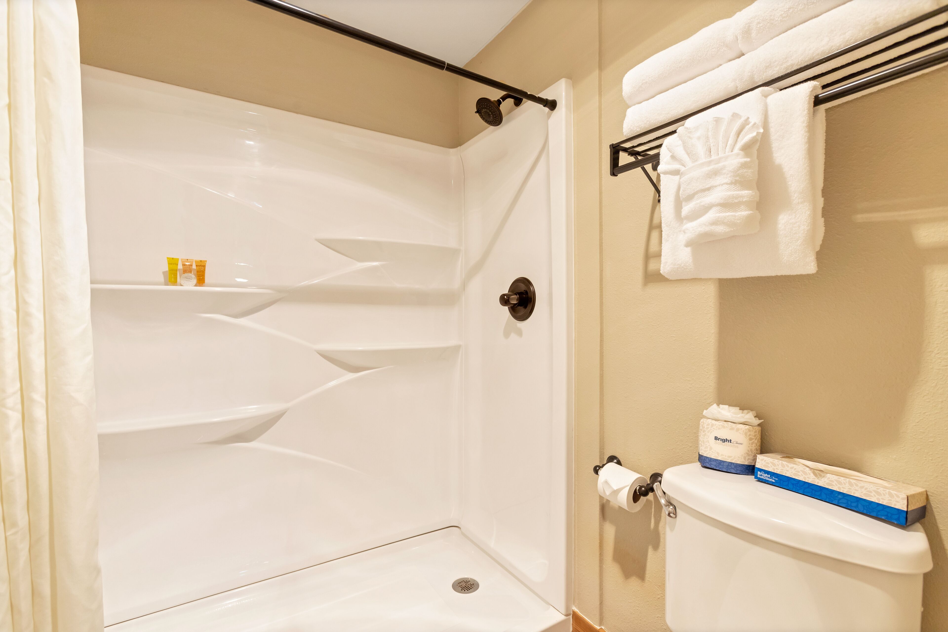 Baño con ducha, inodoro y perchero para toallas.