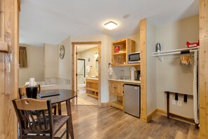 A compact kitchen with wooden cabinetry, a dining table with chairs, and a microwave.