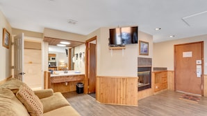 Un salon chaleureux avec un mur d’accent en bois, un téléviseur à écran plat et une cheminée intégrée.