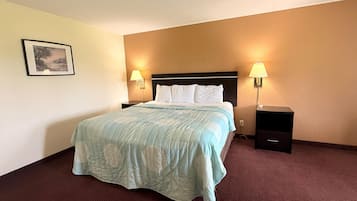 A hotel room with a bed, two bedside lamps, a nightstand, and a framed picture on the wall.