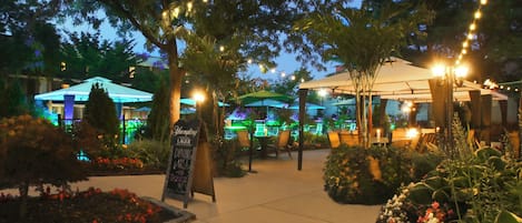 An outdoor dining area with string lights, umbrellas, and a sign for Yuengling lager.