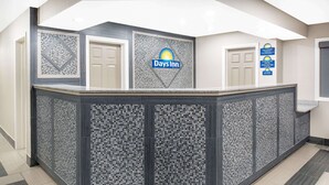 A reception area with a Days Inn logo, a check-in counter, and a sign indicating a 24-hour check-in service.