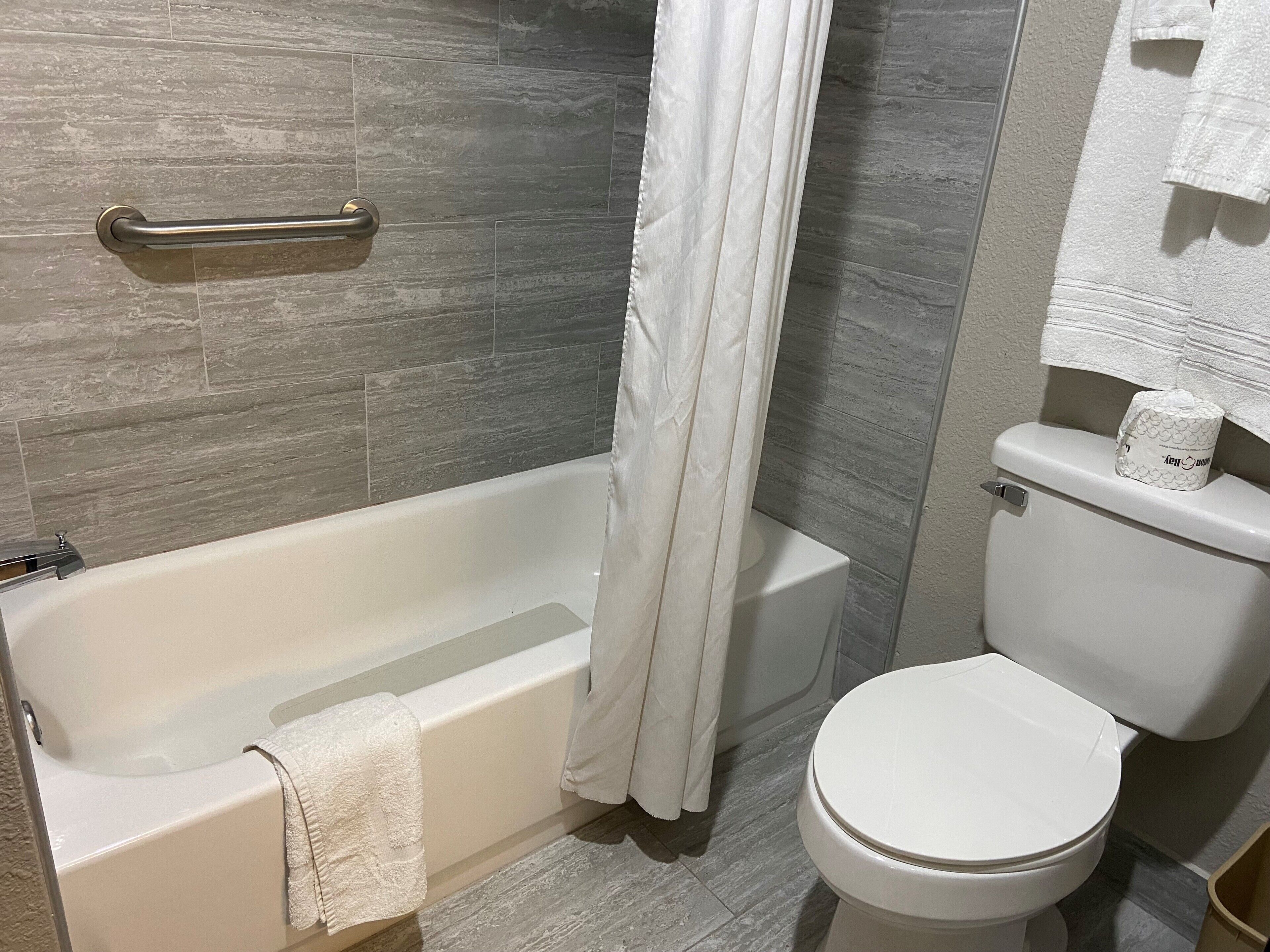 A bathroom with a bathtub, toilet, and a shower curtain.