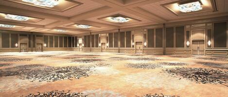 A spacious conference room with a patterned carpet, recessed lighting, and a high ceiling.
