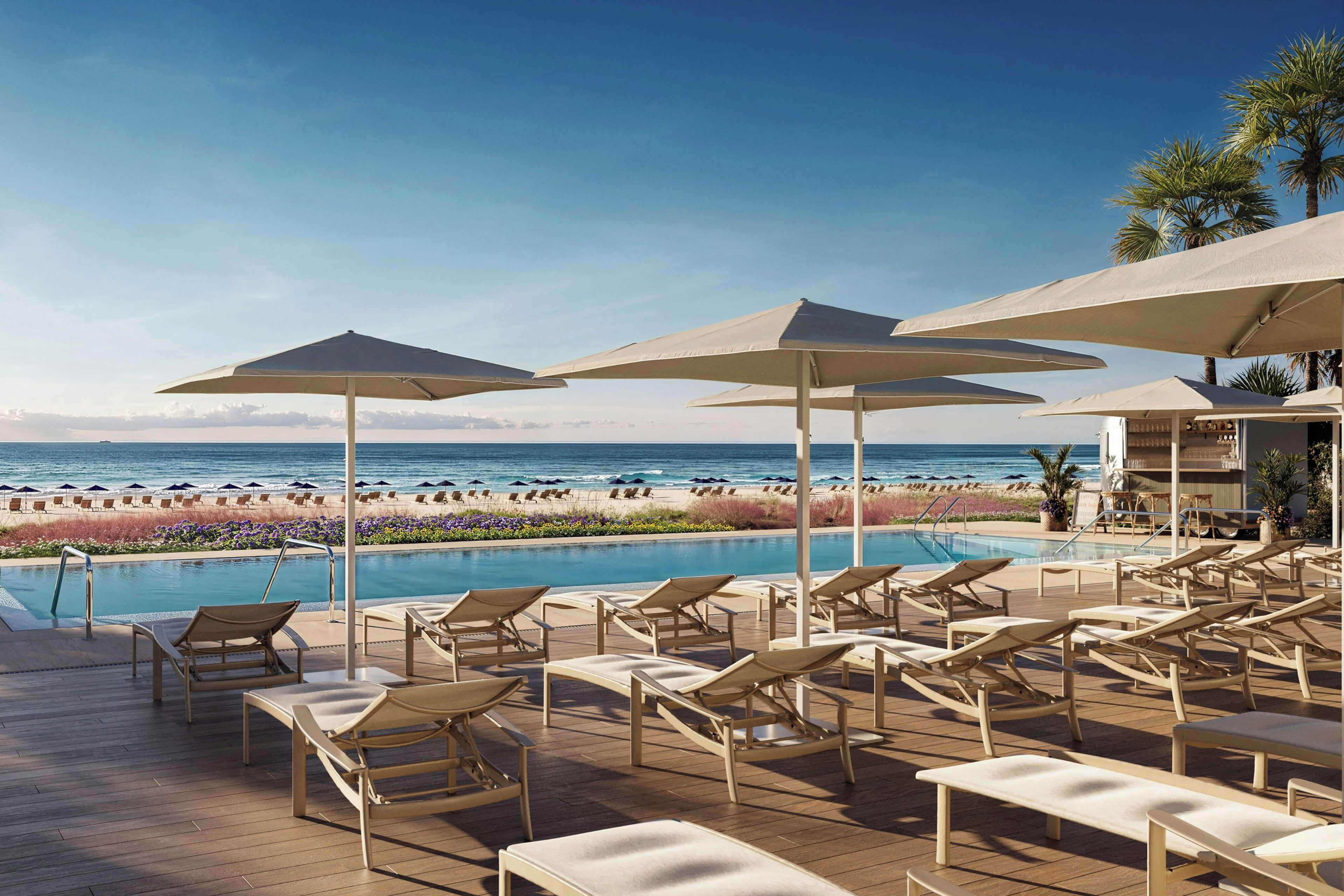 A poolside area with lounge chairs and umbrellas overlooking a beach.