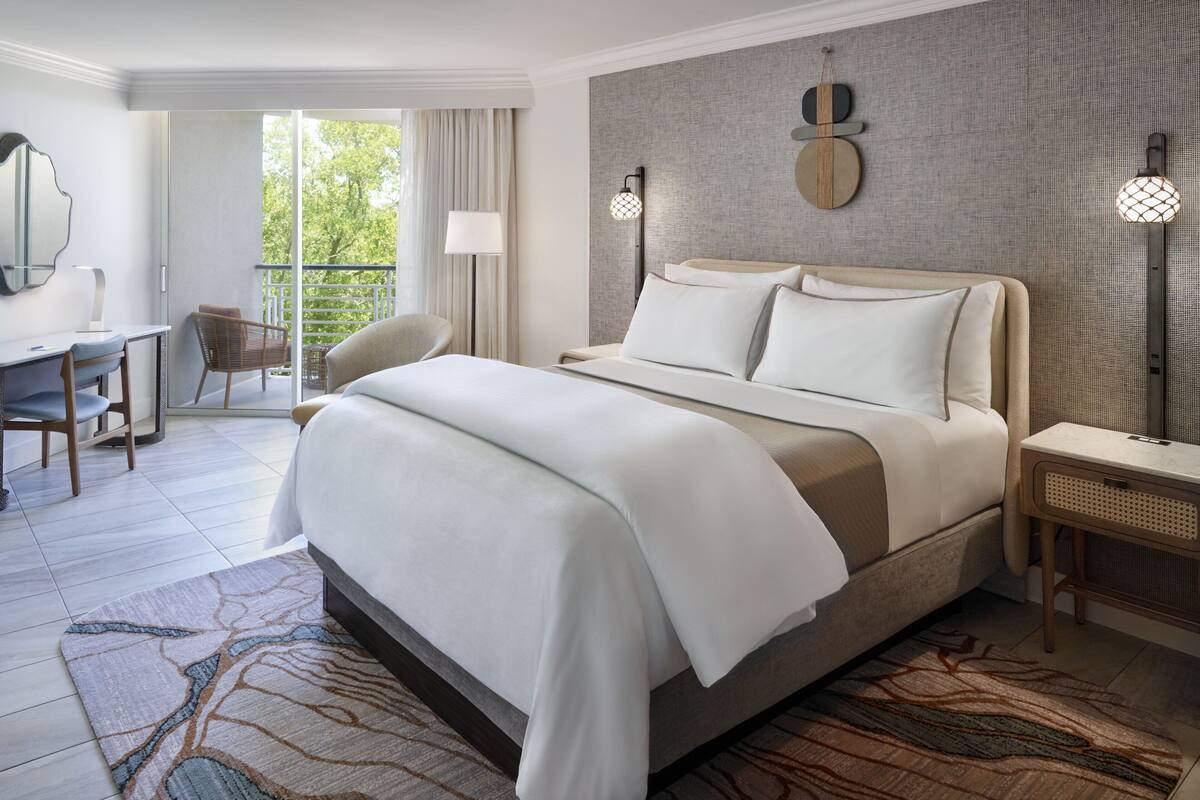 Ein modernes Hotelzimmer mit einem großen Bett, einem Schreibtisch und einem Stuhl.