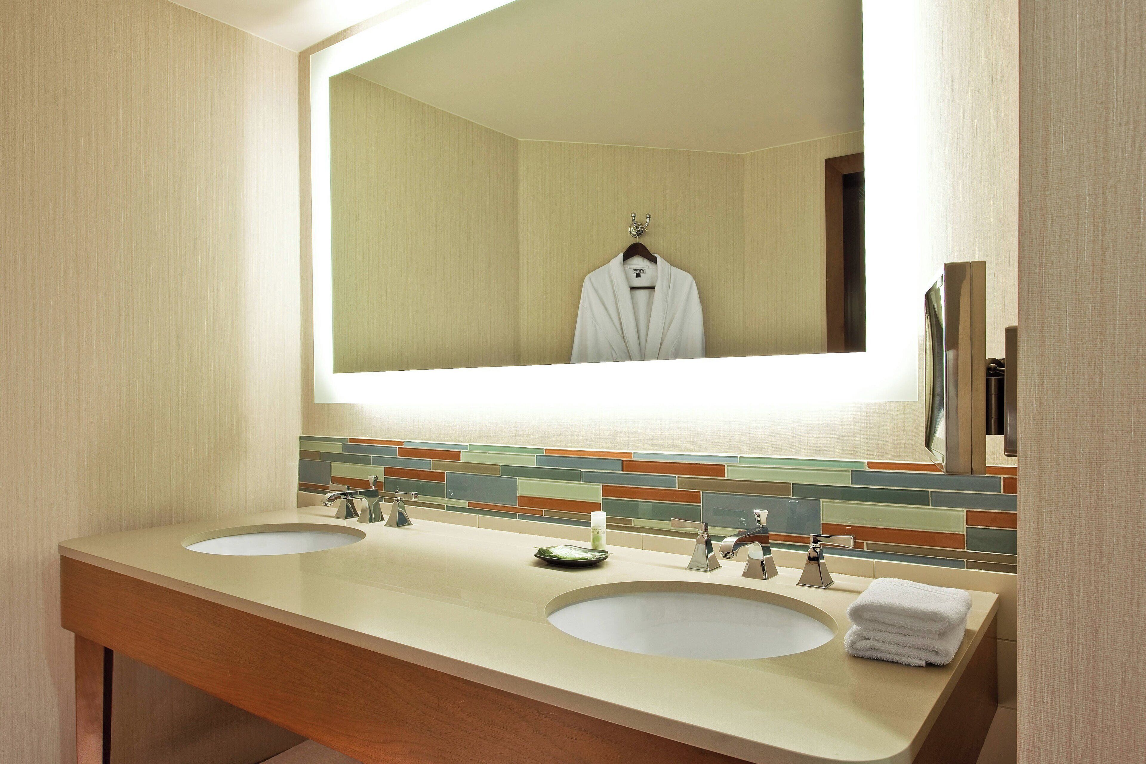 A bathroom with two sinks, a mirror, and a towel rack.