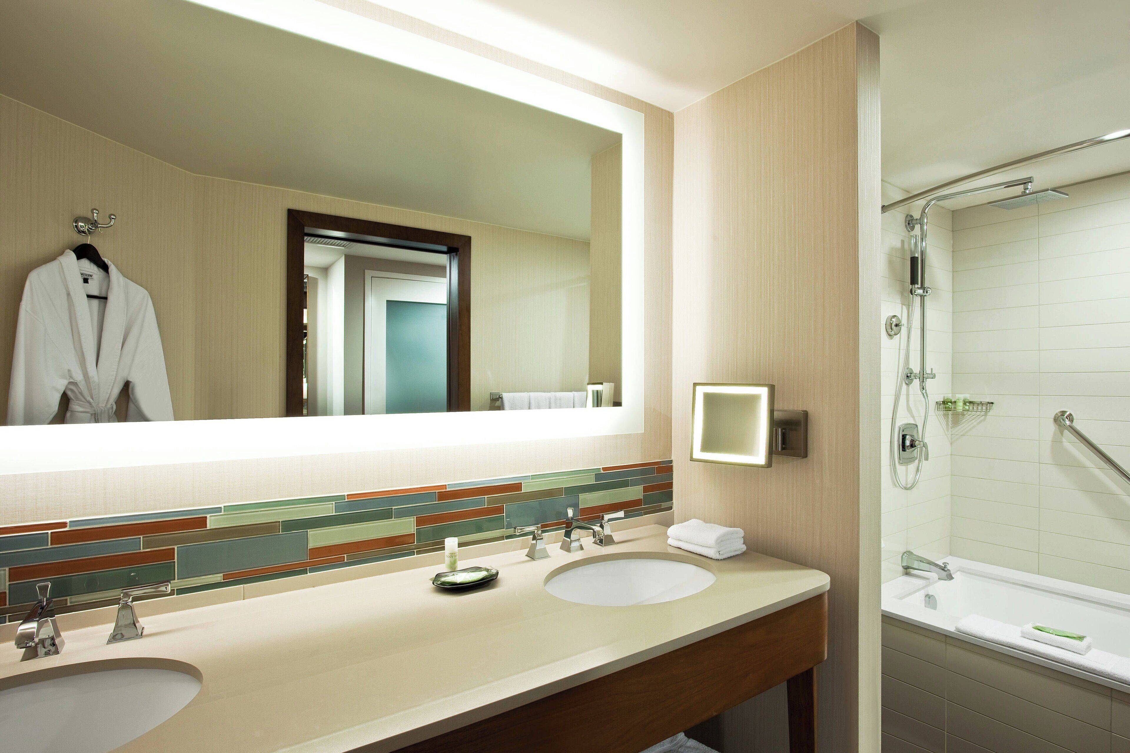 Une salle de bain moderne avec deux lavabos, un grand miroir et un espace douche.
